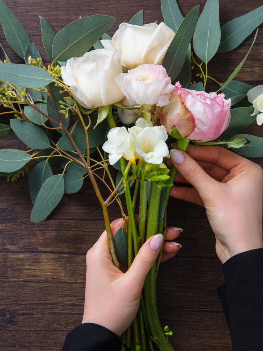 fiorista-al-lavoro-donna-che-fa-moda-moderna-bouquet-di-fiori-diversi-su-una-superficie-di-legno_155003-35265